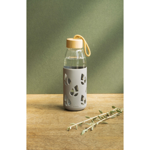 Mise en situation de la bouteille en verre vide Pebbly avec bouchon en bambou et protection grise en silicone