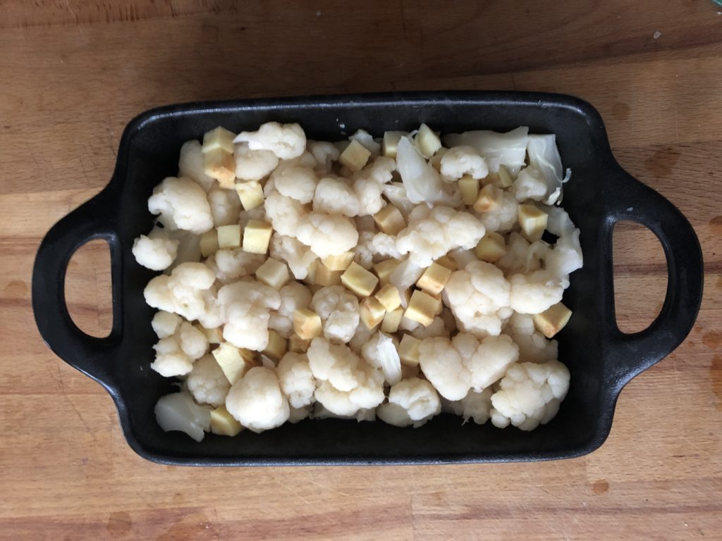 Répartition des légumes cuits à la vapeur dans le plat à gratin.